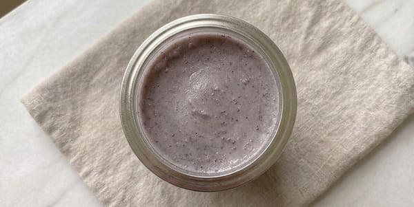 Vue de dessus d'un pot en verre ouvert rempli d'ube halaya violette pâle fraîchement préparée, posé sur un tissu en lin beige sur surface en marbre blanc