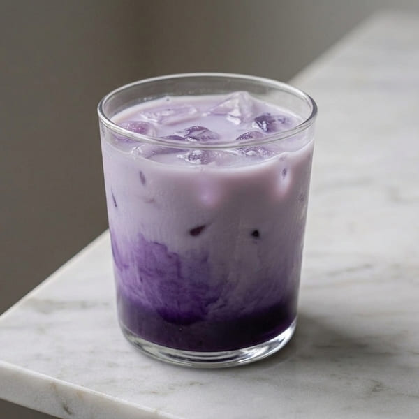 Iced Ube Barista Latte avec dégradé violet naturel sur lait blanc et glaçons, préparé avec la poudre Ube Barista Aroma Matcha