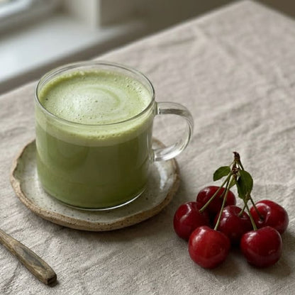 Tasse de matcha cerise latte chaud mousseux avec cerises fraîches, préparé avec la poudre Aroma Matcha