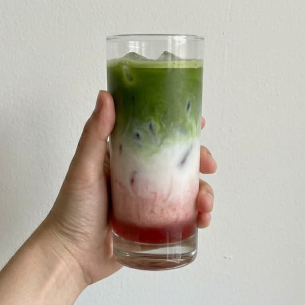 Verre de matcha cerise latte glacé avec dégradé rouge et vert, préparé avec la poudre premium Aroma Matcha